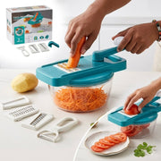 Person using a blue vegetable chopper to shred carrots and tomatoes on a white surface with additional attachments.