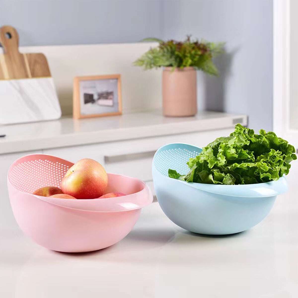 Two Plastic Rice Washing Strainer Baskets with fruits and vegetables in it placed on a kitchen counter top 