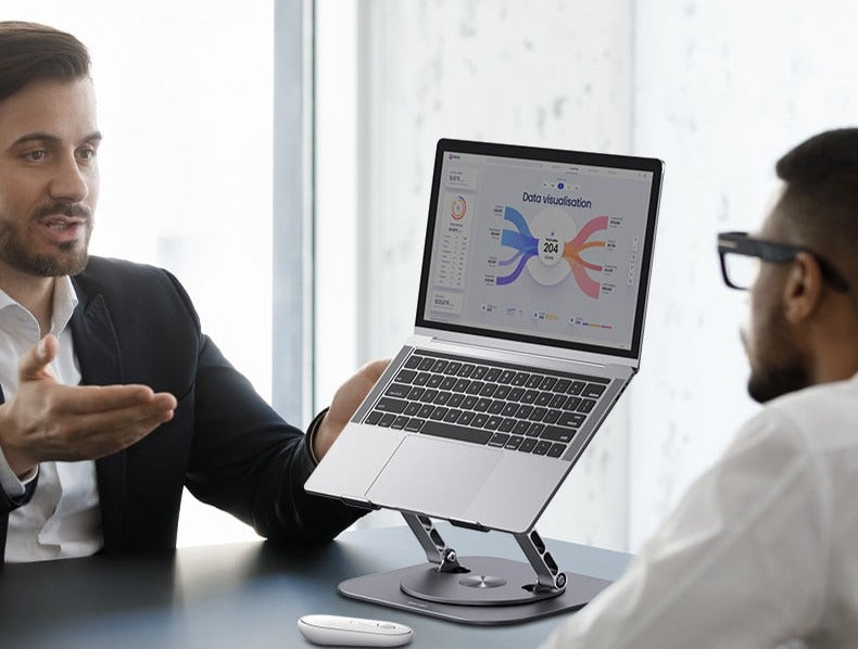  Two individuals engage in conversation while standing before a laptop placed on an Adjustable Laptop Stand.