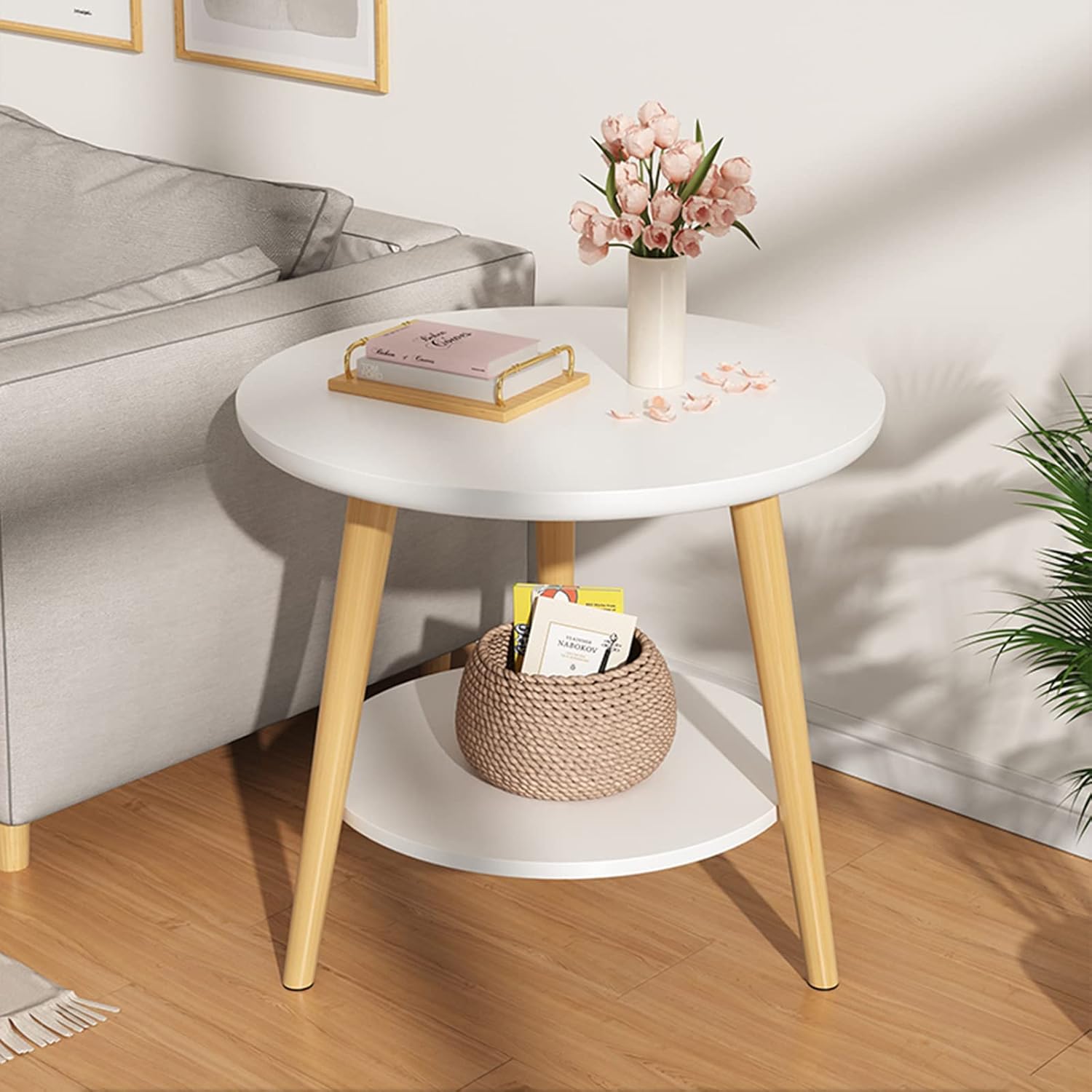 Modern round side table with wooden legs, decorated with books, flowers, and a woven basket,On a cozy living room