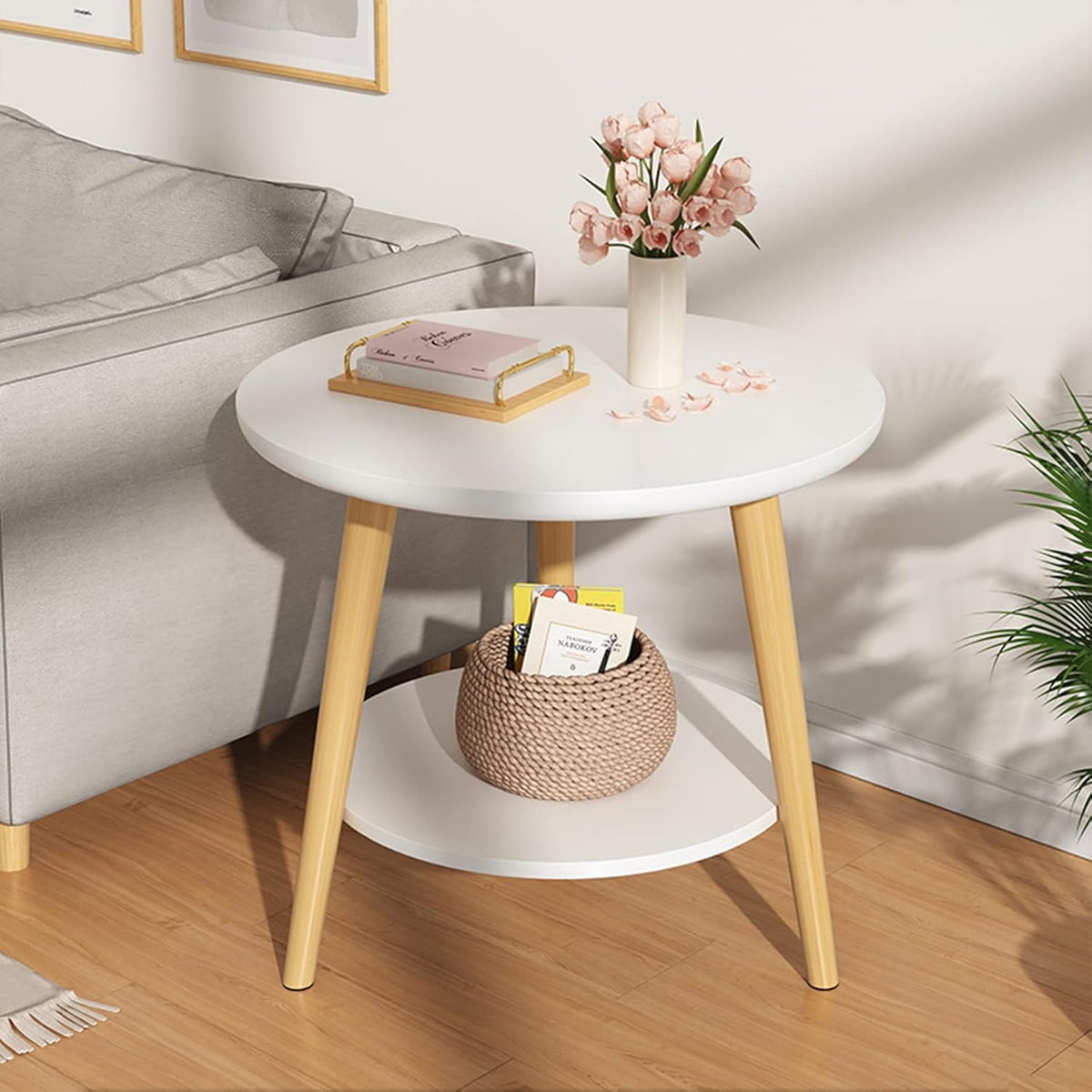 Modern round side table with wooden legs, decorated with books, flowers, and a woven basket,On a cozy living room