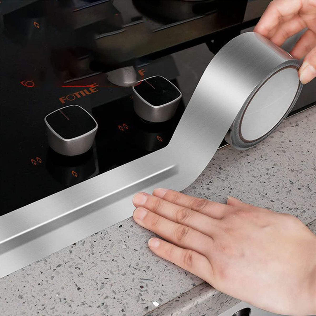 A person sticking Leakproof Aluminum Foil Tape beside of gas stove on a counter top 
