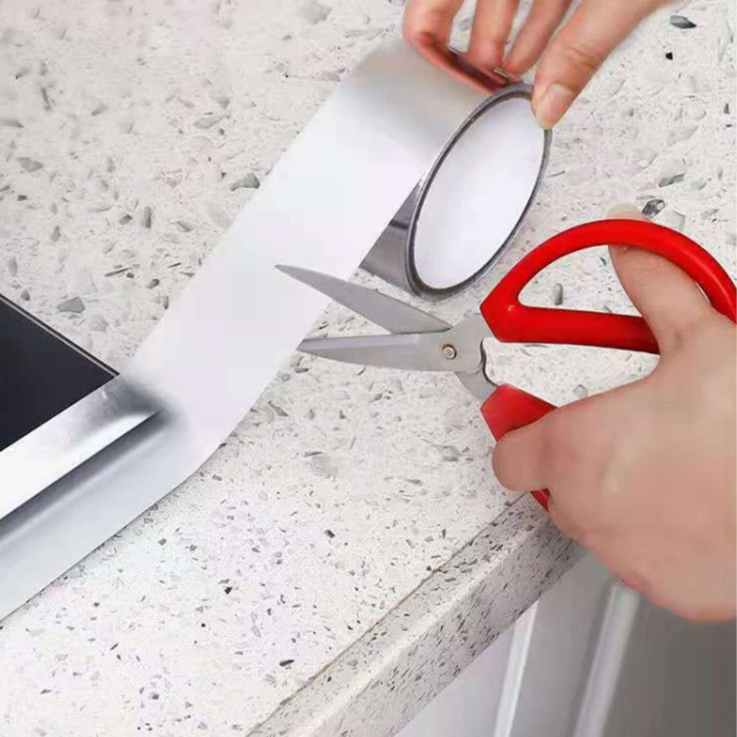 A person cutting Leakproof Aluminum Foil Tape with a scissor after sticking it on a counter top