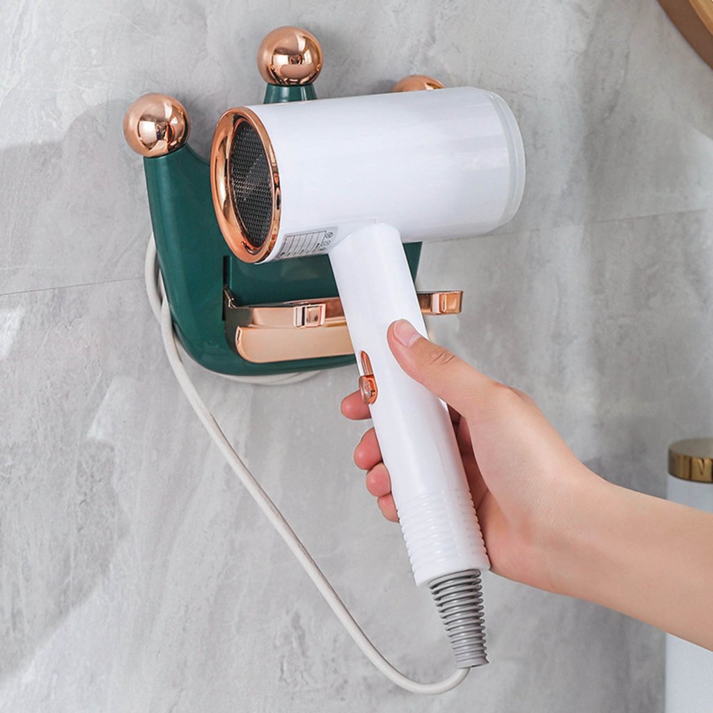A person stands in front of a wall-mounted hair dryer holder, using a blow dryer to dry their hair.