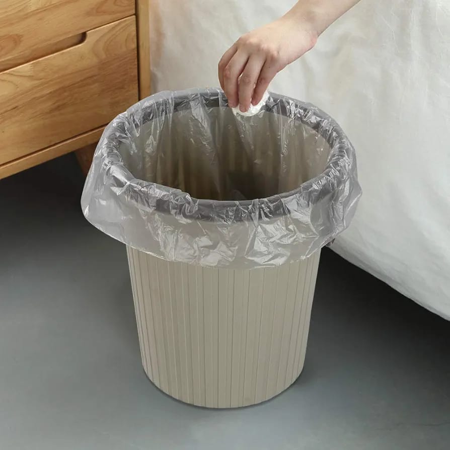 A Person Throwing a Waste on to Garbage Bag Which is Kept in Trash Bucket.