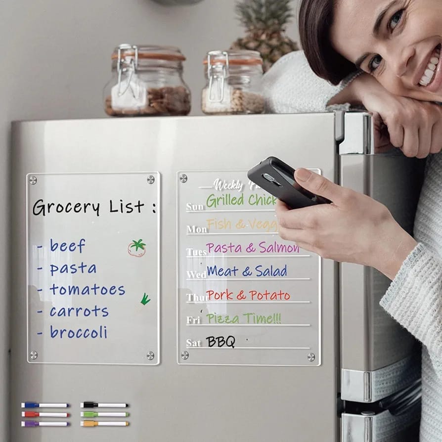 A Women Standing Near A Referigerator Where A Magnetic Weekly Planner Calendar Sticker is Placed On the Door Of Referigerator.