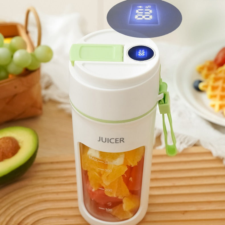 A compact electric juicer filled with fruit pieces, featuring a digital display on the lid, placed on a kitchen counter with fresh fruits around, highlighting convenient and portable blending.