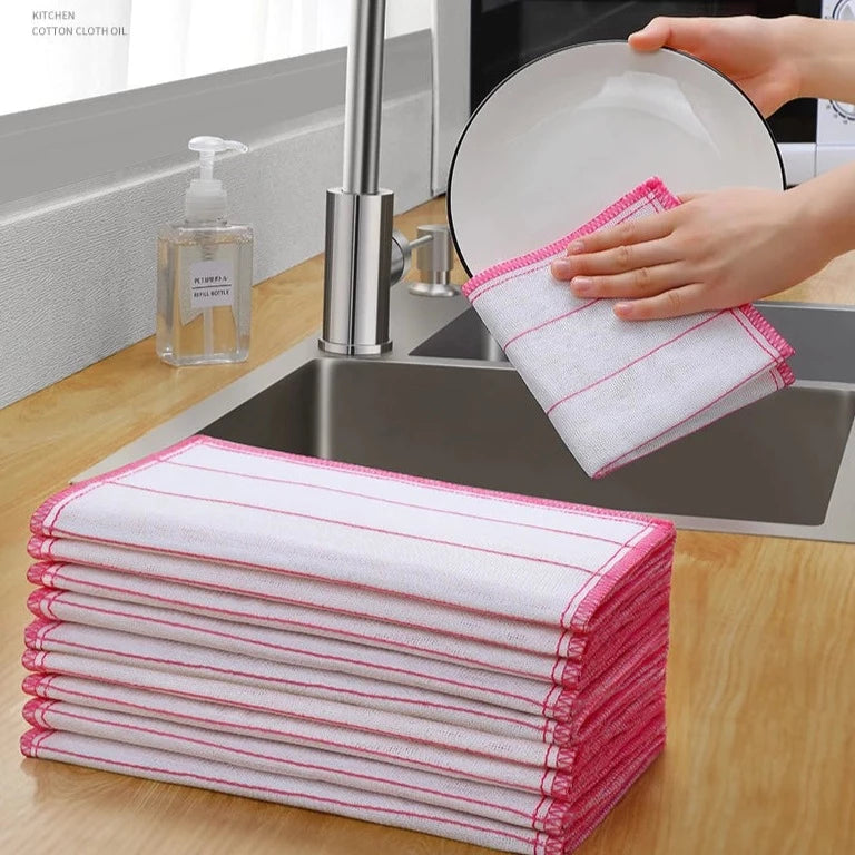 A person is cleaning a plate with the help of a Kitchen Dishwashing Cloth next to a stack of Absorbent Stain Removal Towels