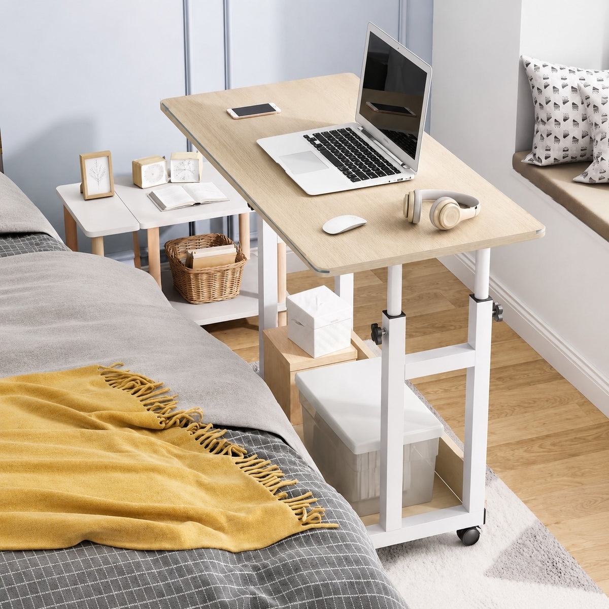 Wooden desk with laptop and accessories on a bed in a bedroom setting