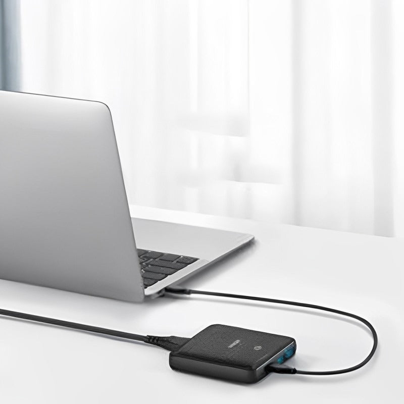 Anker PowerPort Atom III 63W Slim High-Speed Charger with 2 USB-C and 2 USB-A Ports placed on the table next to the laptop, which is plugged into it