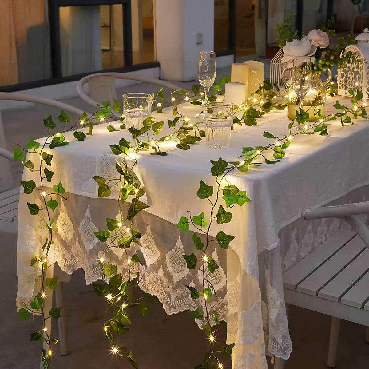 Decorated table with Artificial Ivy Leaf Garland LED String Lights, and candles in an outdoor setting.
