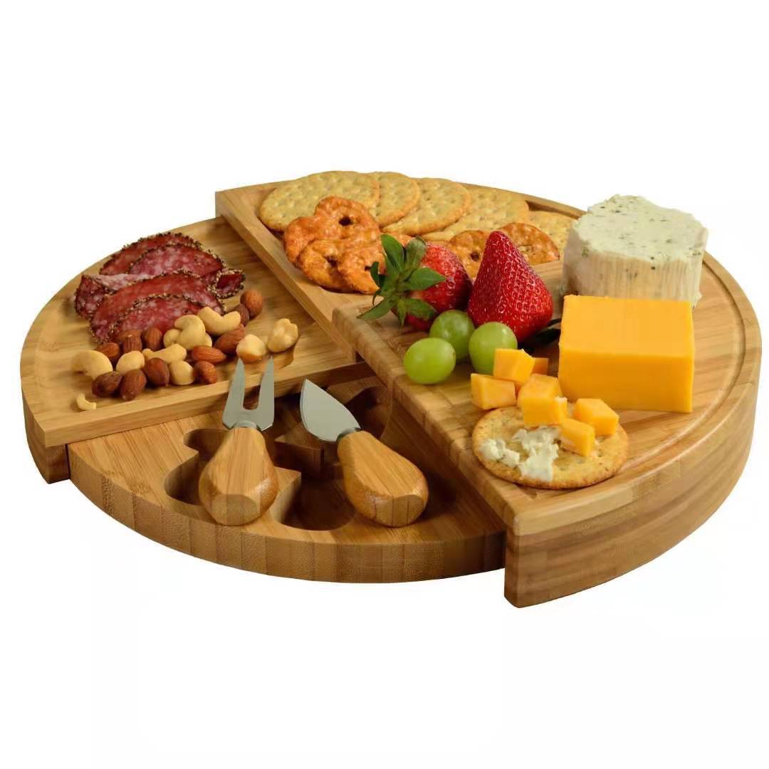 Bamboo cheese board and knife set with an assortment of cheeses, crackers, grapes, nuts.