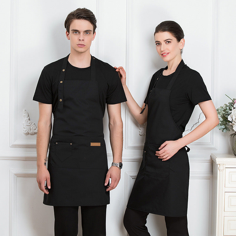 A Men and Women is Wearing Black Unisex Adjustable  Kitchen Chef Apron.