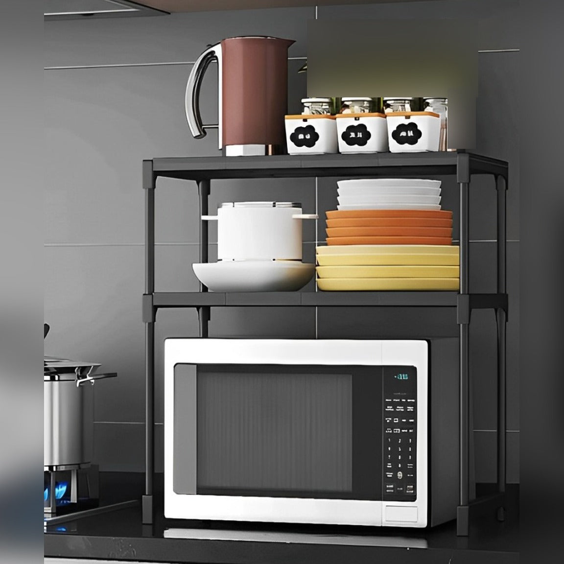 Black double-layer rack organizing Plates, flask and a  microwave on a countertop