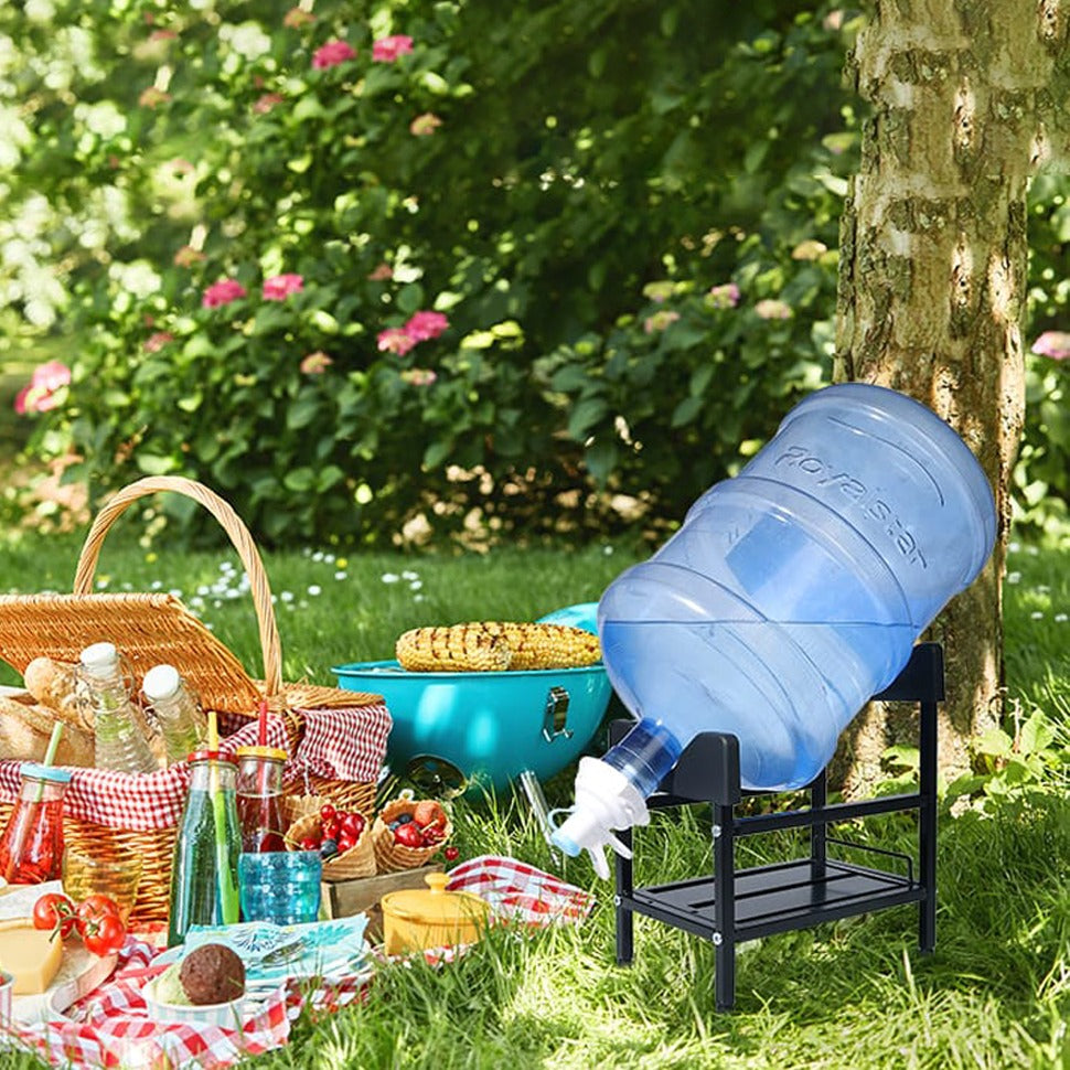 A large blue water jug sits on metal dispenser stand in a grassy outdoor setting