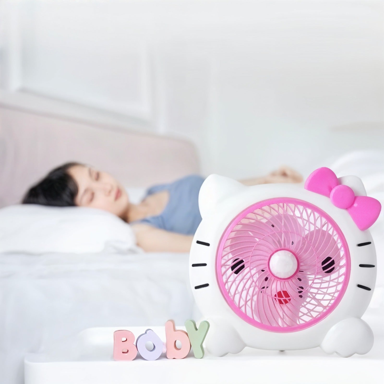 A Child is Sleeping Peacefully and a  Cartoon Mini Desk Personal Fan is Kept Nearby.