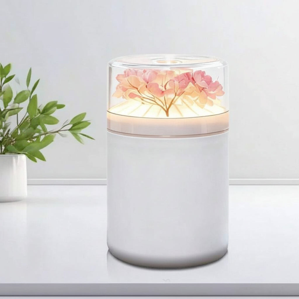 Humidifier with floral design on top, dimensions indicated, and plant in the background.