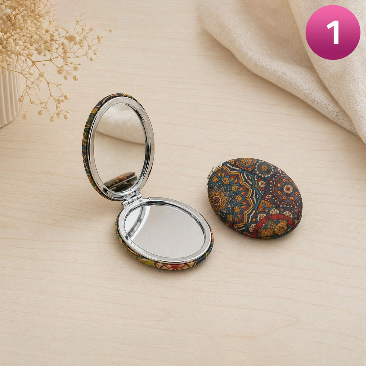 Compact mirror with floral design on a beige surface