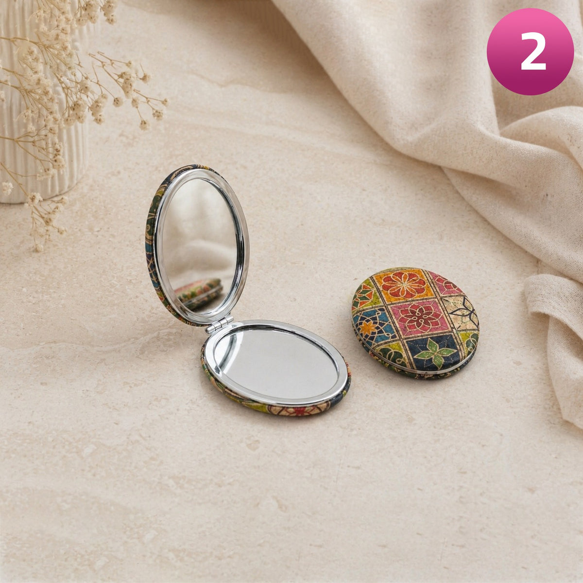 Compact mirror with floral case on a beige fabric background