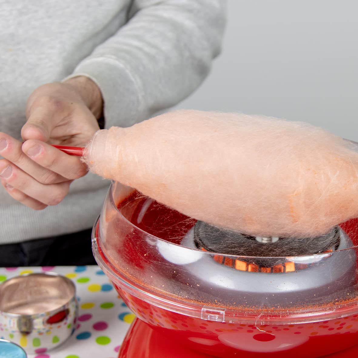 A Person is Making Candy Using Cotton Candy Maker.