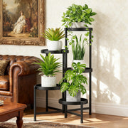 Creative multi-tier metal plant stand with black round shelves, holding multiple indoor potted plants, placed beside a leather sofa in a living room.