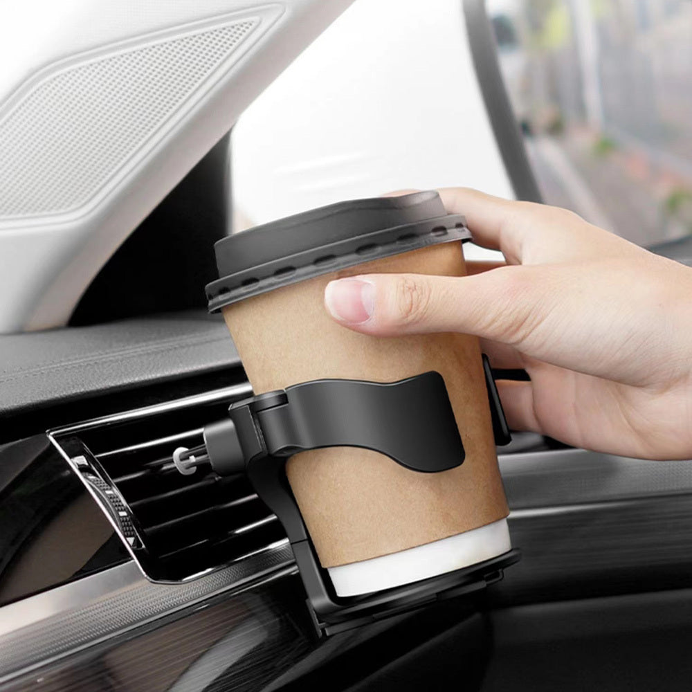 Someone is placing a cup into the Car Cup Holder, which is positioned in the car