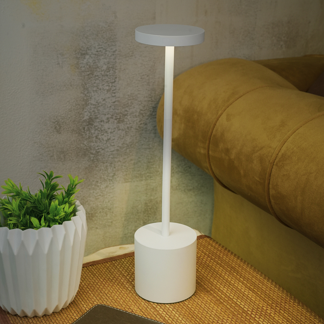 White desk lamp next to a potted plant on a textured surface with a brown couch in the background