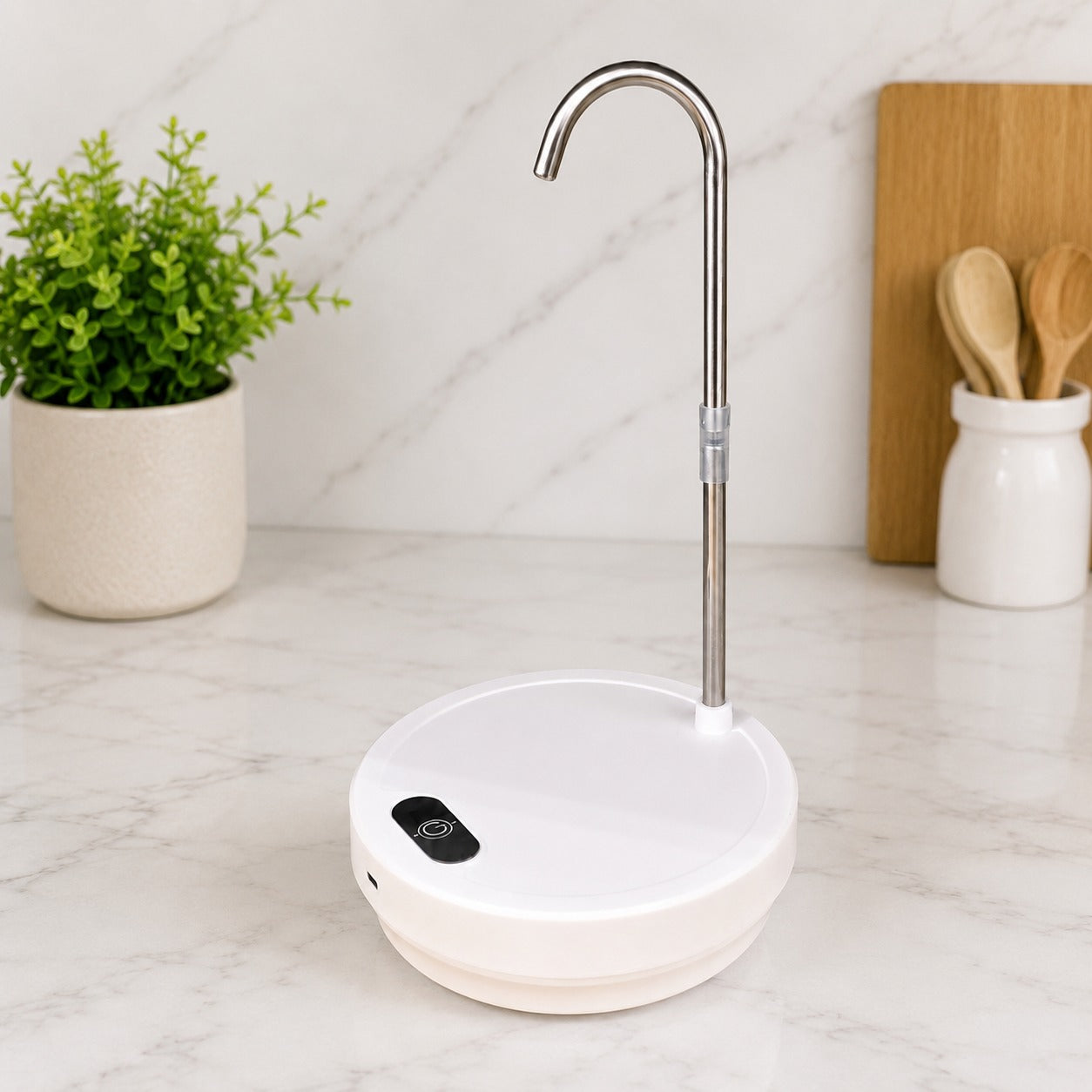 A Desktop Dual-Use Electric Water Pump with a curved stainless steel spout, shown on a white marble countertop with a potted plant and wooden cutting board in the background.