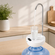 A Desktop Dual-Use Electric Water Pump with a curved stainless steel faucet pouring clear water into a glass, placed on top of a large blue water bottle jug in a bright kitchen setting.