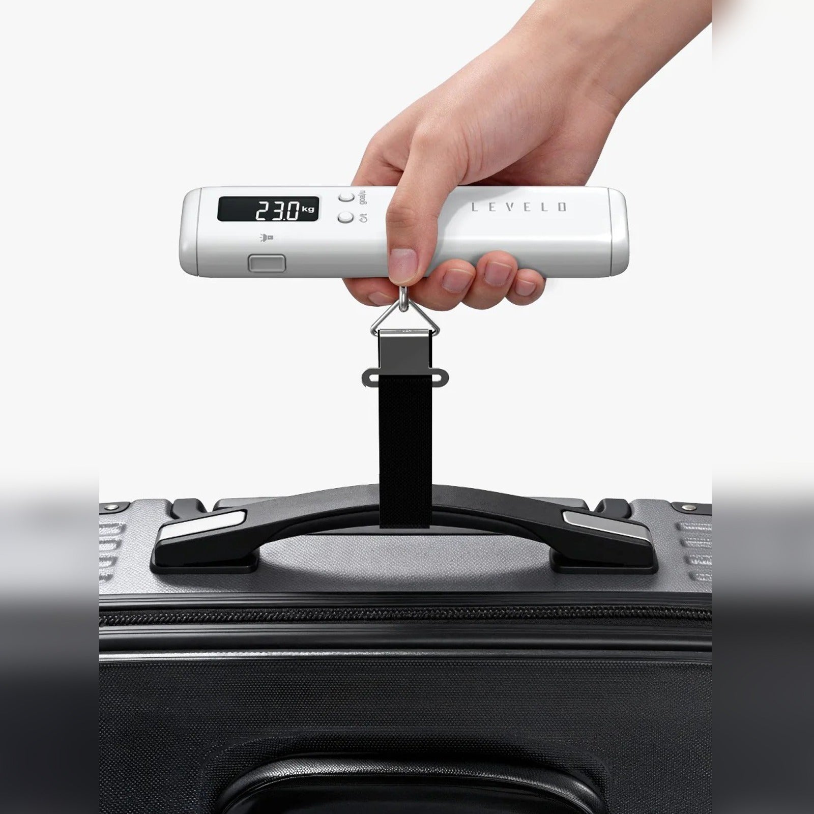 Handheld digital luggage scale measuring a suitcase at 23.0 kg.