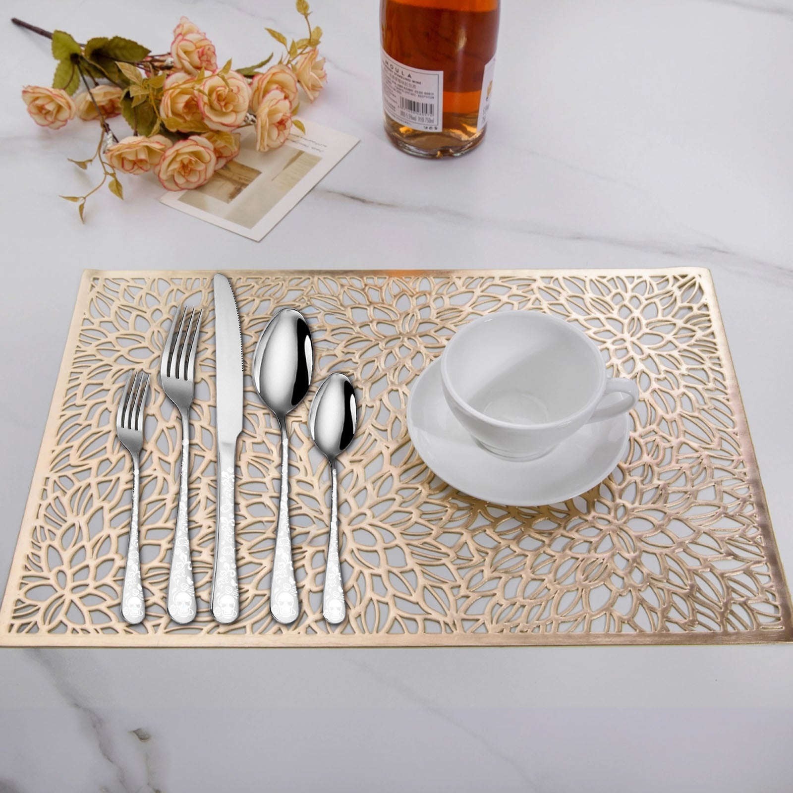 Decorative placemat with cut-out patterns, silverware, and a cup on a table.