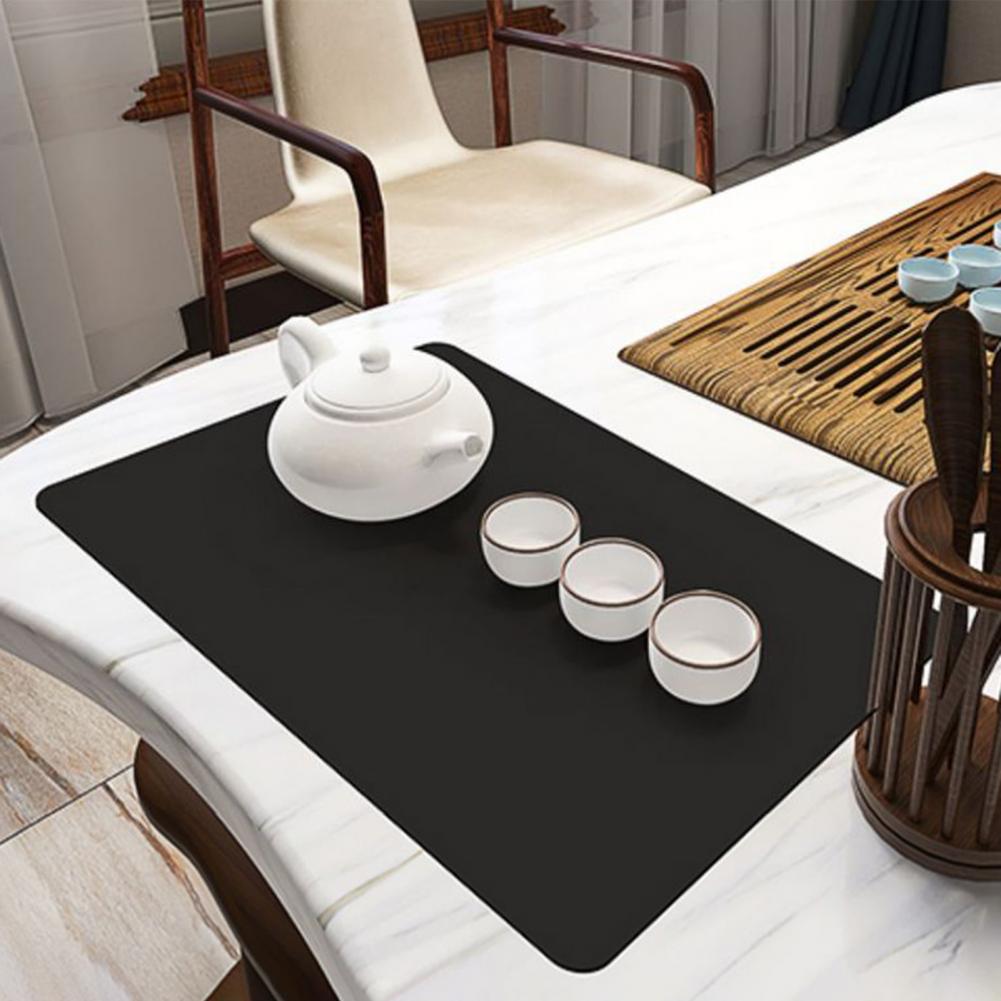 Tea Pot and Cups Are Placed on Dish Drying Mat Which is at Dining Table.