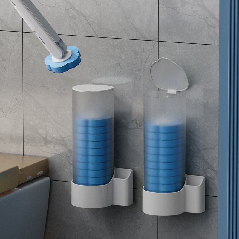 Disposable Head Toilet Cleaning Brush with Long Handle with frosted tops and blue circular inserts, mounted on a gray tiled wall. One holder is open with its lid raised, and a hand holding a blue-and-white applicator is visible in the upper left.