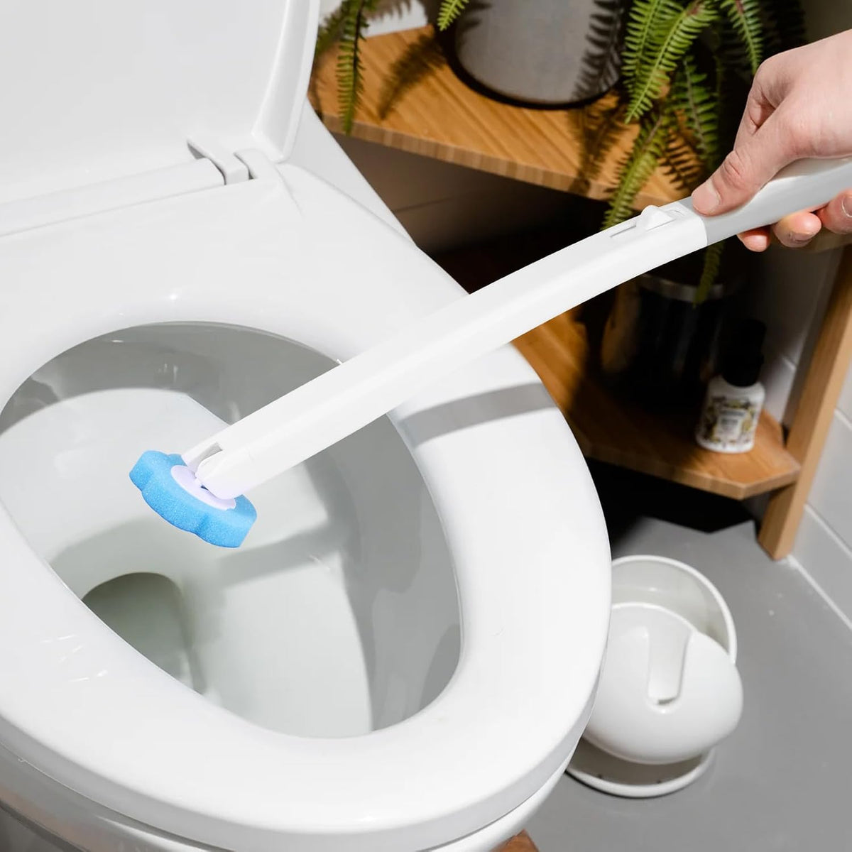 A Person is holding Disposable Head Toilet Cleaning Brush with Long Handle.