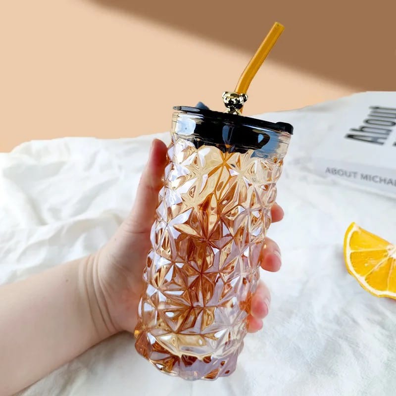 A Person is Holding Drinking Glass Tumbler With Straw and Lid.