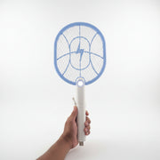 Hand holding a blue and white electric fly swatter on a tiled floor.