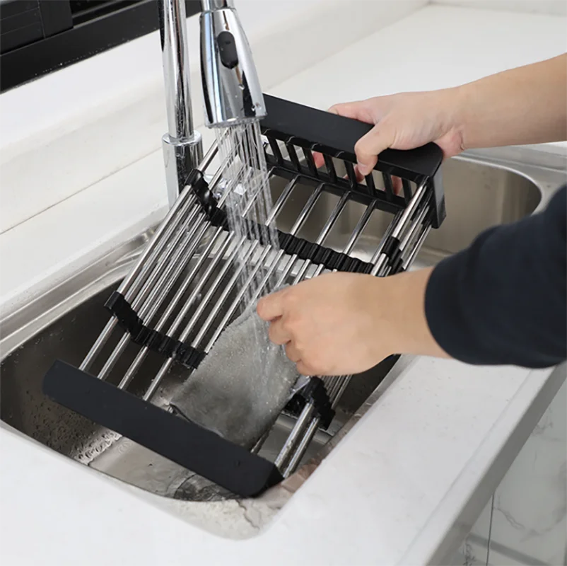 Someone cleaning an expandable dish drying and washing basket