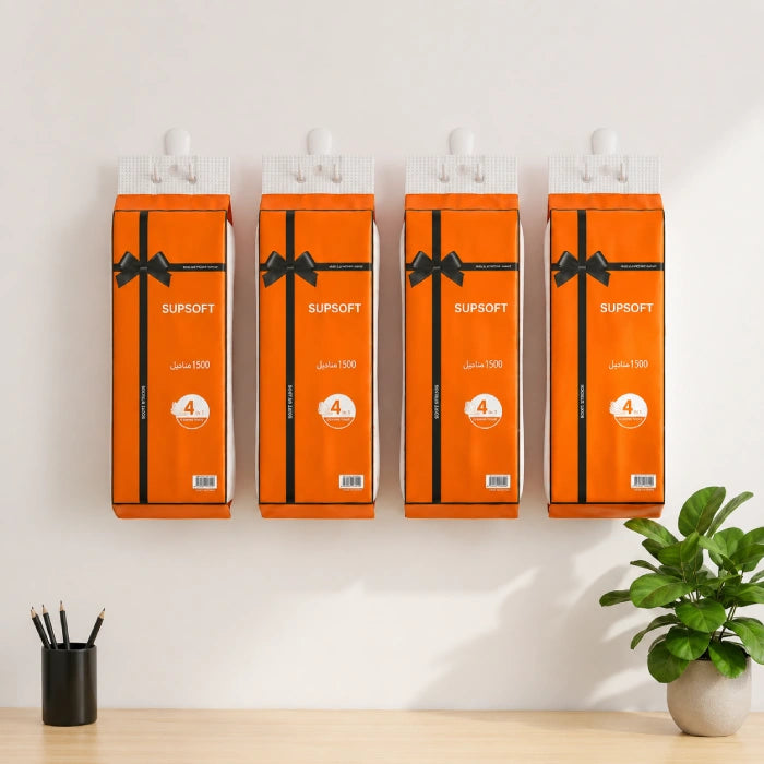 Four orange boxes labeled 'Supsoft' Extra Soft Tissue Pack on a white wall with a plant and pen holder in the foreground.