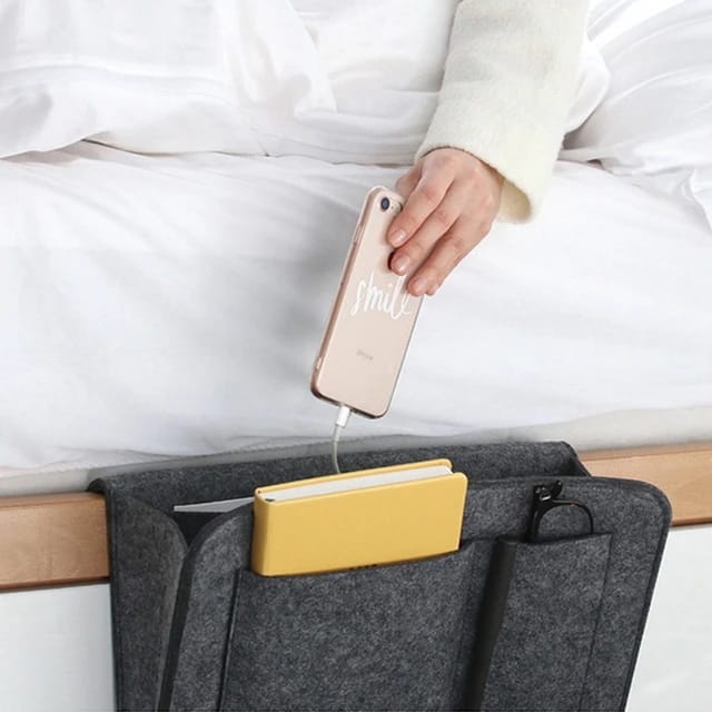 Someone taking a phone from the Felt Bedside Storage Bag
