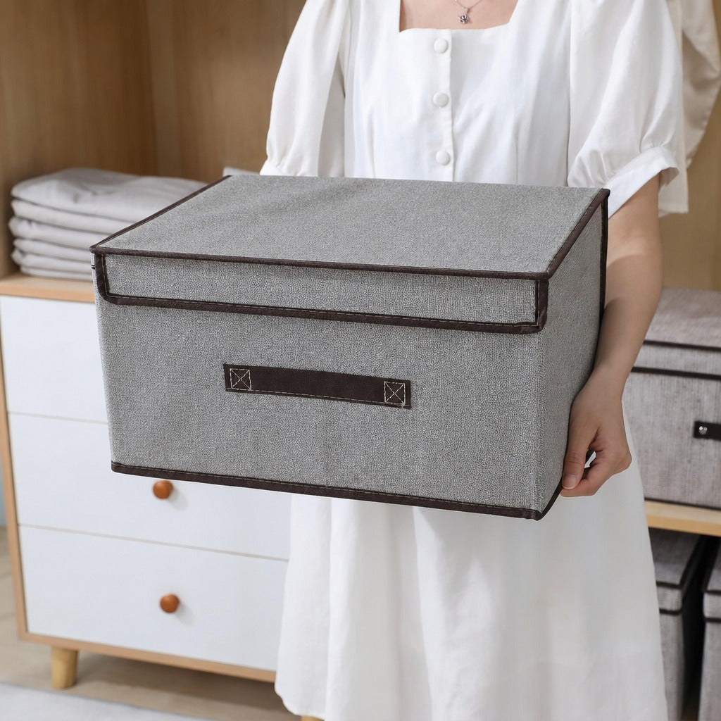 Person holding a Foldable Fabric Storage Box with a brown lid in a room setting.