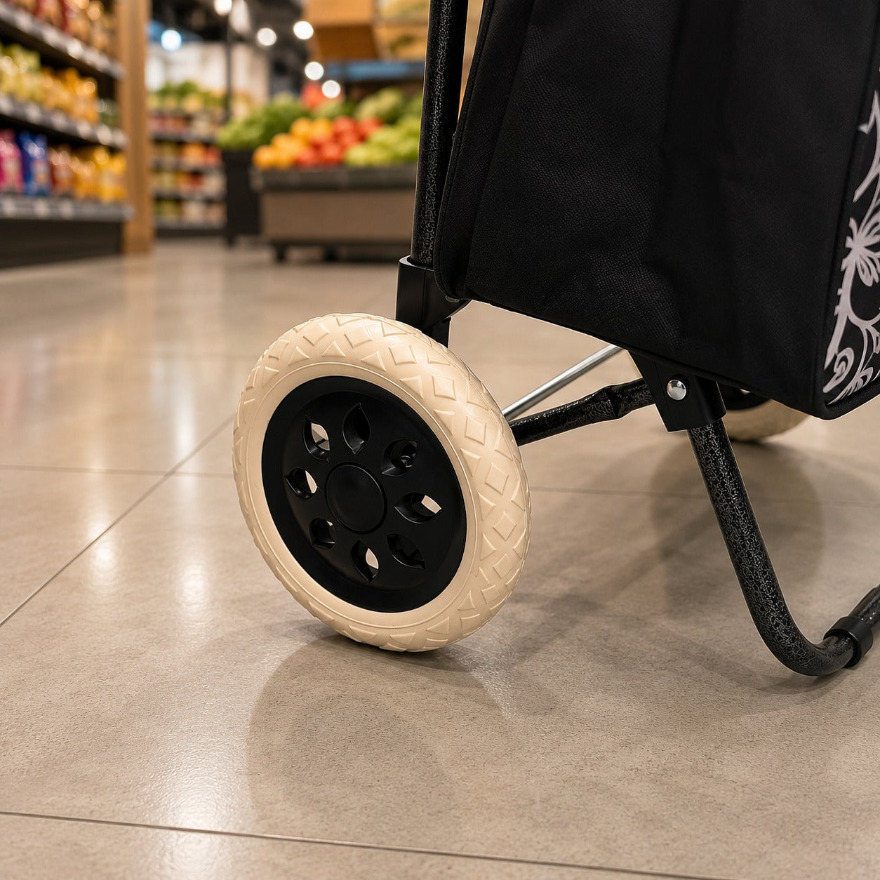 A close-up of a black shopping cart wheel with a cream-colored treaded outer tire, positioned on a polished tile floor inside a grocery store.