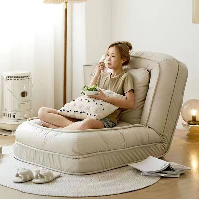 A Women is Sitting and Eating Fruits In a Folding Lazy Sofa.