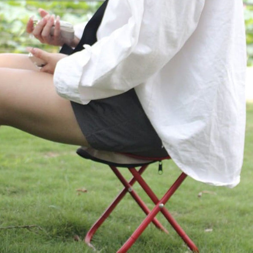 A Person is Sitting On a Folding Small Stool.