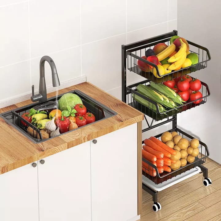 Adjustable Fruit Vegetable Basket Cart placed on the floor, stocked with vegetables and fruits, next to a sink