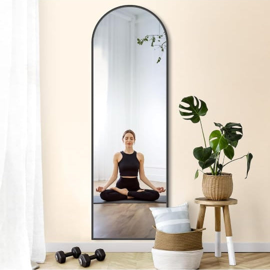 A Full-Length Arched Standing Floor Mirror with Stand Reflecting a Lady.