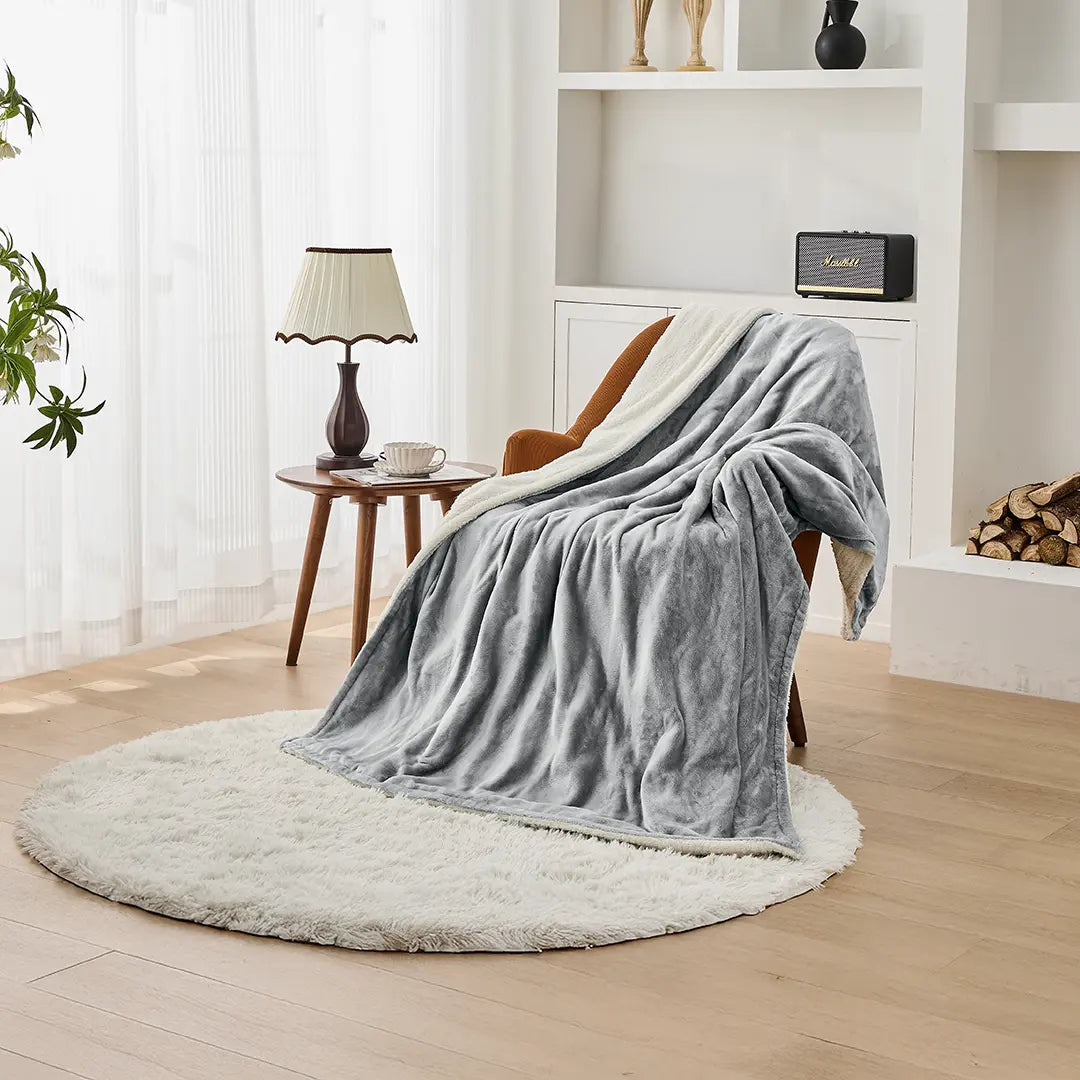 A gray Green Lion Electric Blanket draped over a chair in a cozy living room setting.