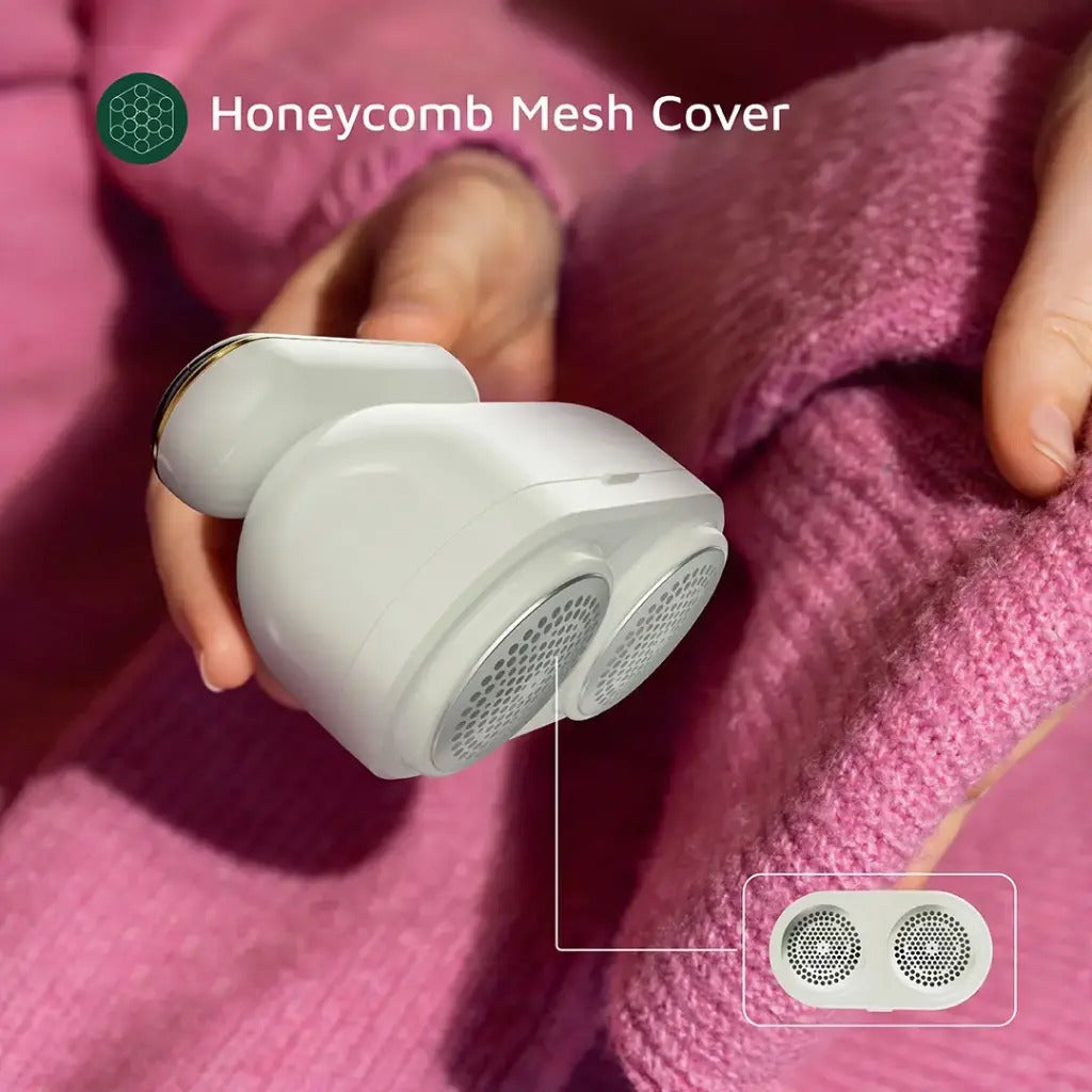  A person using the Green Lion DualPro Digital Fabric Remover on a pink sweater. The device features a honeycomb mesh cover designed to safely remove lint and fuzz without damaging the fabric. The close-up highlights its dual-head mesh design for efficient and even fabric care.