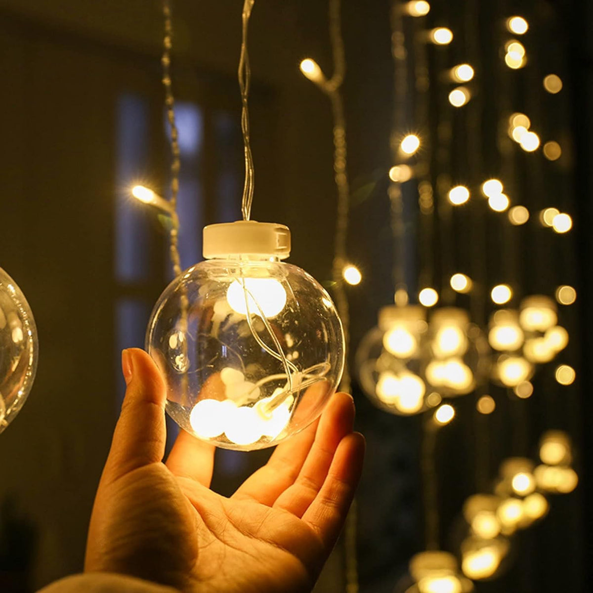 A Peron is Holding Hanging Ball String Light.