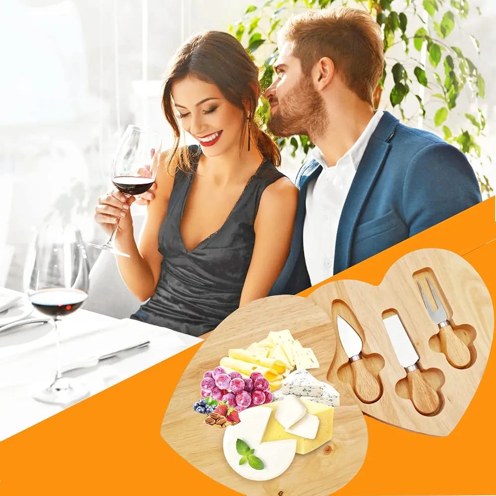 A couple is partying by using a heart-shaped wooden cheeseboard with built-in knife storage and a serving area for cheese and crackers.