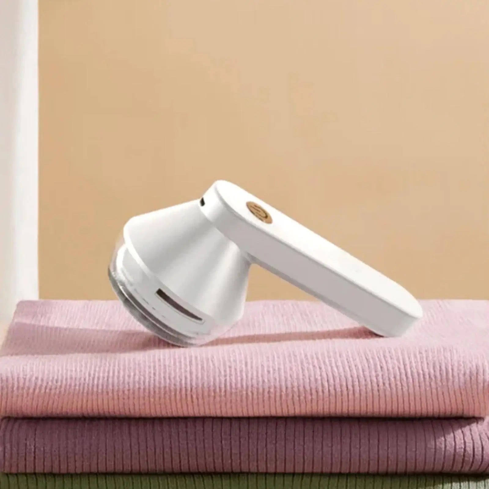 A Portable USB Rechargeable Lint Remover is placed on a stack of towels